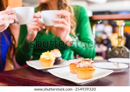 Friends having fun and eating muffins at bakery or pastry shop 
