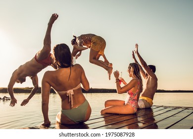 Friends Having Fun Enjoying A Summer Day Swimming And Jumping At The Lake.