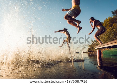 Friends having fun enjoying a summer day swimming and jumping at the lake.