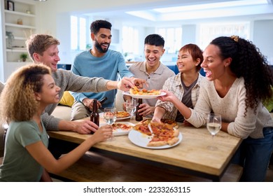 Friends Having Fun At Home In Kitchen Eating Homemade Pizzas - Powered by Shutterstock