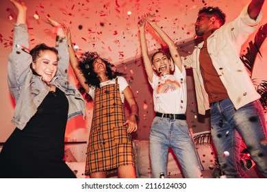 Friends having fun at a house party. Group of cheerful friends dancing to their favourite song under falling confetti. Multicultural friends enjoying their weekend together. - Powered by Shutterstock