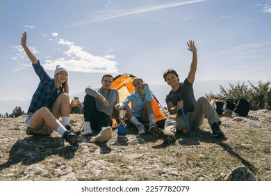 Friends having fun at the mountain while sitting infront of the tent