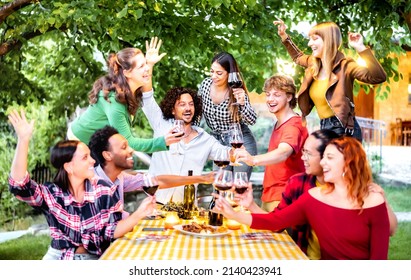 Freunde, die sich bei Gartenparty beim Rotweintoasting amüsieren - Lebensartiges Konzept mit Menschen, die nachts im Weingut zusammen essen und trinken - Schiefertiefe und selektiver Fokus