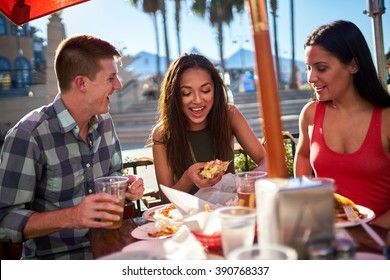 Friends Having Fun At Outdoor Restaurant Eating And Drinking