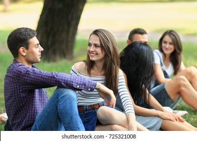 Friends Having Fun In Park, Focus On Young Woman And Man Communicating With Each Other. Relationship, Friendship, Youth, Good Company Concept. Photo Of Group People On Summer Day Outdoors