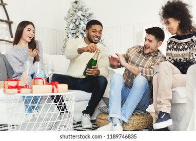 Friends Having Fun While Popping Cork On New Year Champagne Bottle, One Guy Scared By Splash, Copy Space