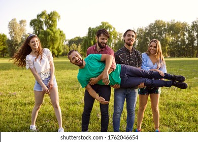 Friends Having Fun In Wilderness During Their Summer Trip In Park. Group Of People Being Silly Outdoors