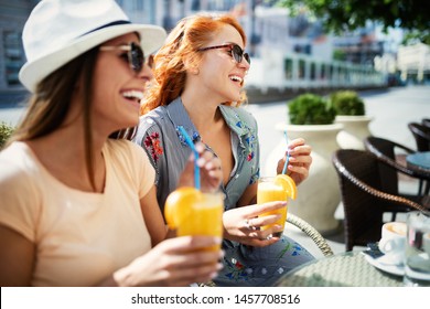 Friends having a great time in cafe. Women smiling and drinking juice and enjoying together