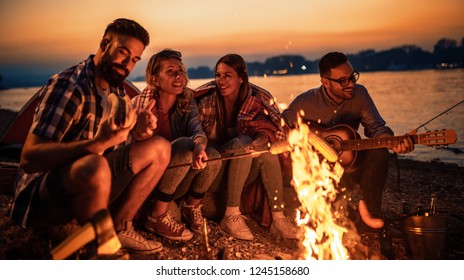 Friends having picnic around the fire.Group of young friends having picnic at night. - Powered by Shutterstock