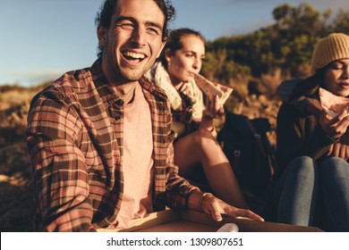 Friends Having Pizza Sitting On Mountain Trail During Their Hiking Trip. Group Of Man And Woman On Hiking Trip Eating Pizza.