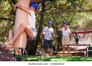 Friends Help Each Other Overcome Water Obstacles In Theme Park. High Quality Photo