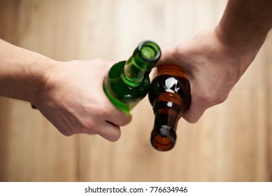 Friends hold beer bottles close-up above top view