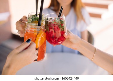 Friends holding glasses of summer cocktails and toasting. Lifestyle concept. Outdoors.
