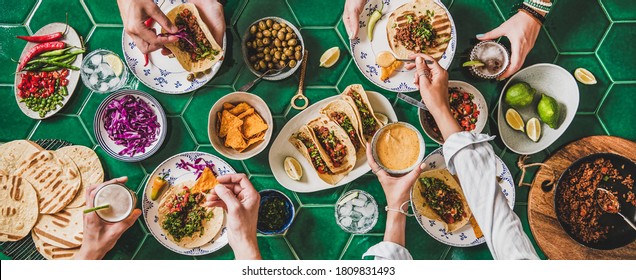 Freunde zu Hause Taco Party. Flach gelegene mexikanische traditionelle Gerichte Tacos mit Rindfleisch, Maistortillas , Tomatensalsa und Völker mit Lebensmitteln auf grünem Hintergrund, Draufsicht. mexikanische Küche