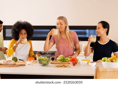 Friends in kitchen drinking smoothies and preparing healthy meal together. cooking, lifestyle, vegetables, preparation - Powered by Shutterstock