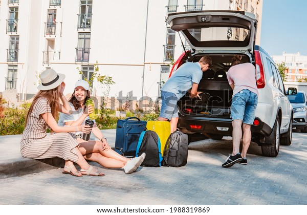 friends load car trunk with baggage. summer
road trip vacation.