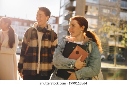 Friends Looking Away While Walking Outdoors With Friends In College. Cheerful Students Walking In University Outdoors.