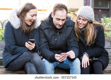 Friends Looking On Phone Outside In Winter