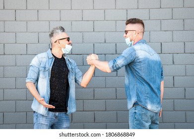 Friends With Lowered Protective Masks Doing Greetings With Handshake During Coronavirus Outbreak - Two Friends Who No Longer Respect Social Distancing - New Normal Concept After Coronavirus Outbreak