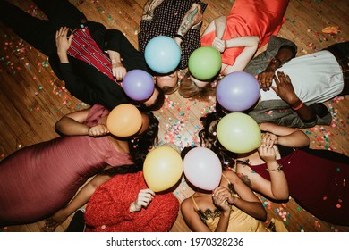 Friends lying on the floor at a party with balloons 