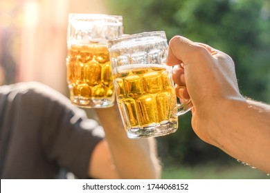 Friends Making A Beer, Talking And Laughing In A Garden With The Sun Light At Summer. Drink Safety. Cheers. Close Up.