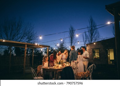 Friends Making Big Party In The Night. Group Of People Having At Garden Restaurant At Night.