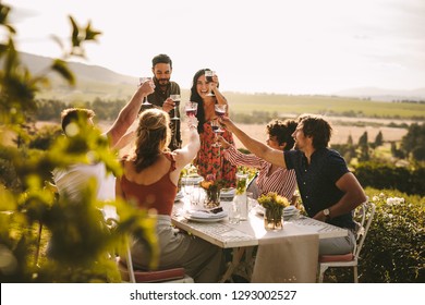 Friends making big party outdoors. Group of people toasting wine during a dinner party. - Powered by Shutterstock