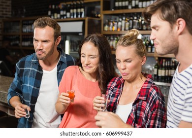 Friends making faces because of shots in a bar