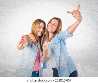 Friends making horn gesture over textured background