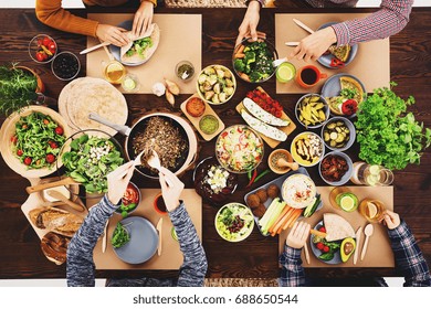 Friends meeting at a vegan dinner with hummus, falafels and vegetables - Shutterstock ID 688650544