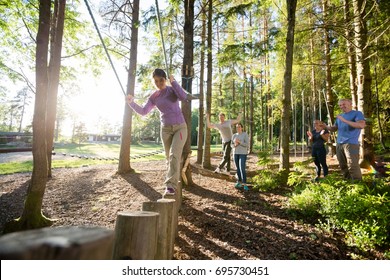 Friends Motivating Woman Crossing Log Bridge In Forest - Powered by Shutterstock