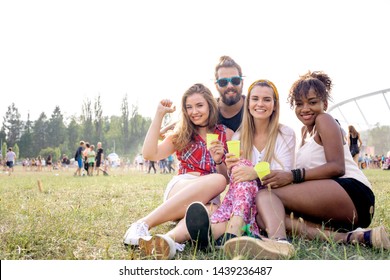 Friends At Music Festival Sitting On Grass And Having Fun