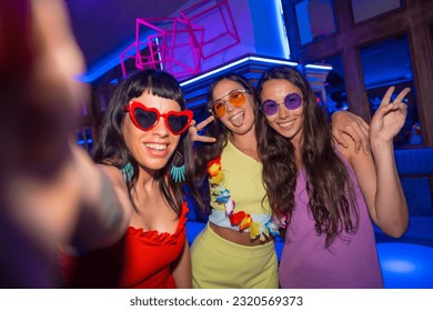 Friends in a nightclub taking a selfie with the phone at a night party on summer vacation in a pub - Powered by Shutterstock