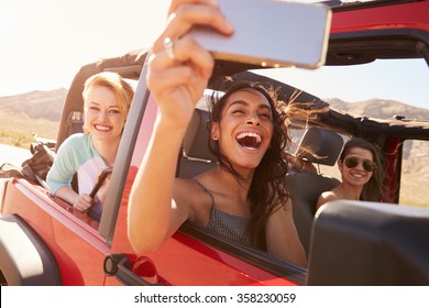 Friends On Road Trip In Convertible Car Taking Selfie - Powered by Shutterstock