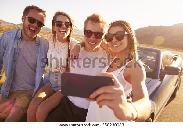 Friends\
On Road Trip Sit On Convertible Car Taking\
Selfie