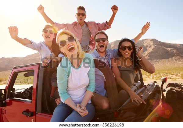 Friends On Road\
Trip Standing In Convertible\
Car