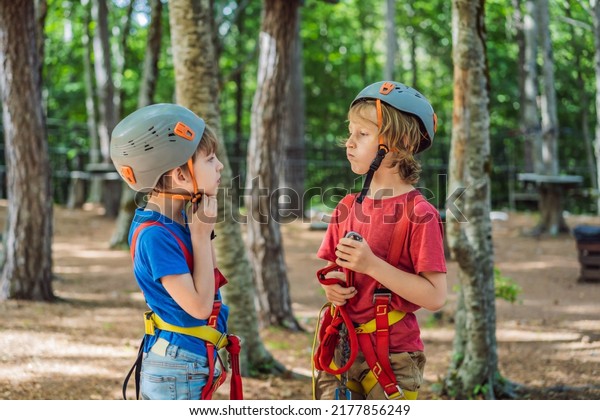 Friends on the ropes course. Young\
people in safety equipment are obstacles on the road\
rope
