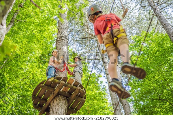 Friends on the ropes course. Young people in safety\
equipment are obstacles on the road rope Portrait of a disgruntled\
girl sitting at a cafe\
table