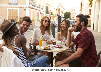 Friends on vacation laughing outside a cafe in Ibiza