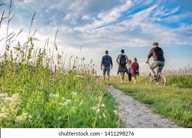 Friends on walk in beautiful rural nature in a landscape behind village. Enjoying happy and funny day and leisure time. Group of young people.