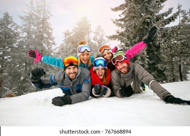 Friends On Winter Holidays â?? Happy Skiers Lying On Snow And Having Fun 