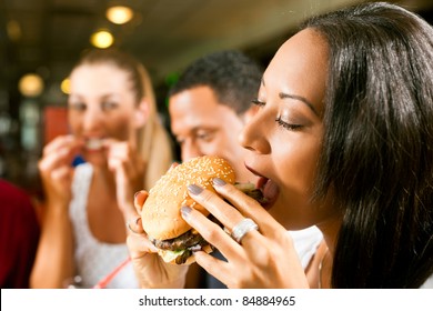 Friends - One Couple Is African American - Eating Hamburger And Drinking Soda In A Fast Food Diner; Focus On The Woman In Front