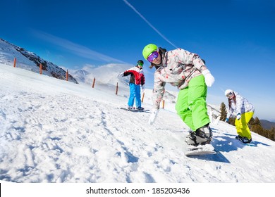 Friends And One Man Is  Snowboarding Downhill