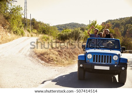 Friends in an open car, passengers standing in the back