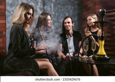 Friends Party In Hookah Lounge. Group Of People Women And Men Smoking Shisha In Cafe Or Bar, Having Fun, Smiling. Relax Concept. Friendship