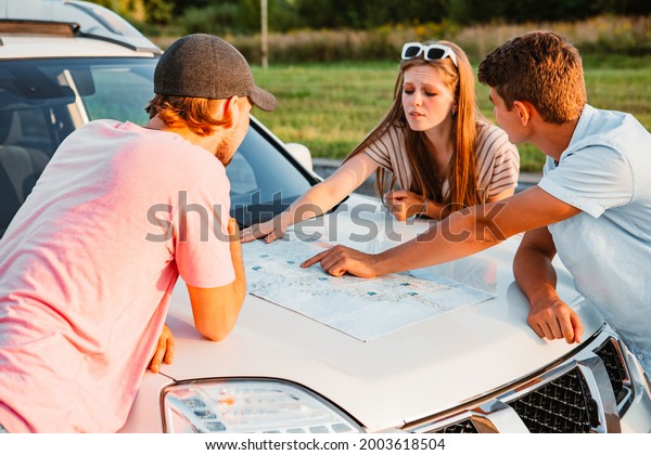 friends\
planning travel destination at car hood sunny\
day