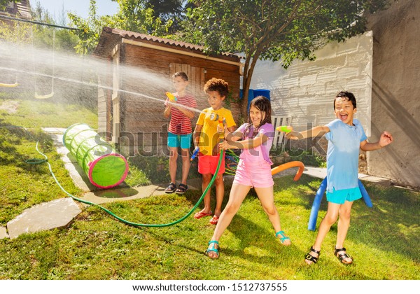 Friends play water gun\
fight in the garden