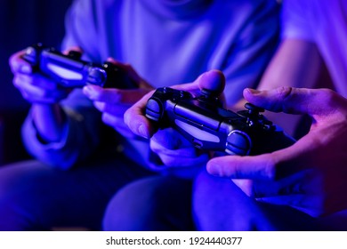friends playing console video games. controller in hands closeup. neon lights