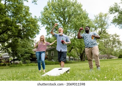 Friends playing cornhole at a summer party in the park