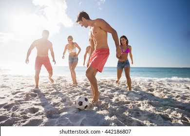 Friends playing football at the beach
